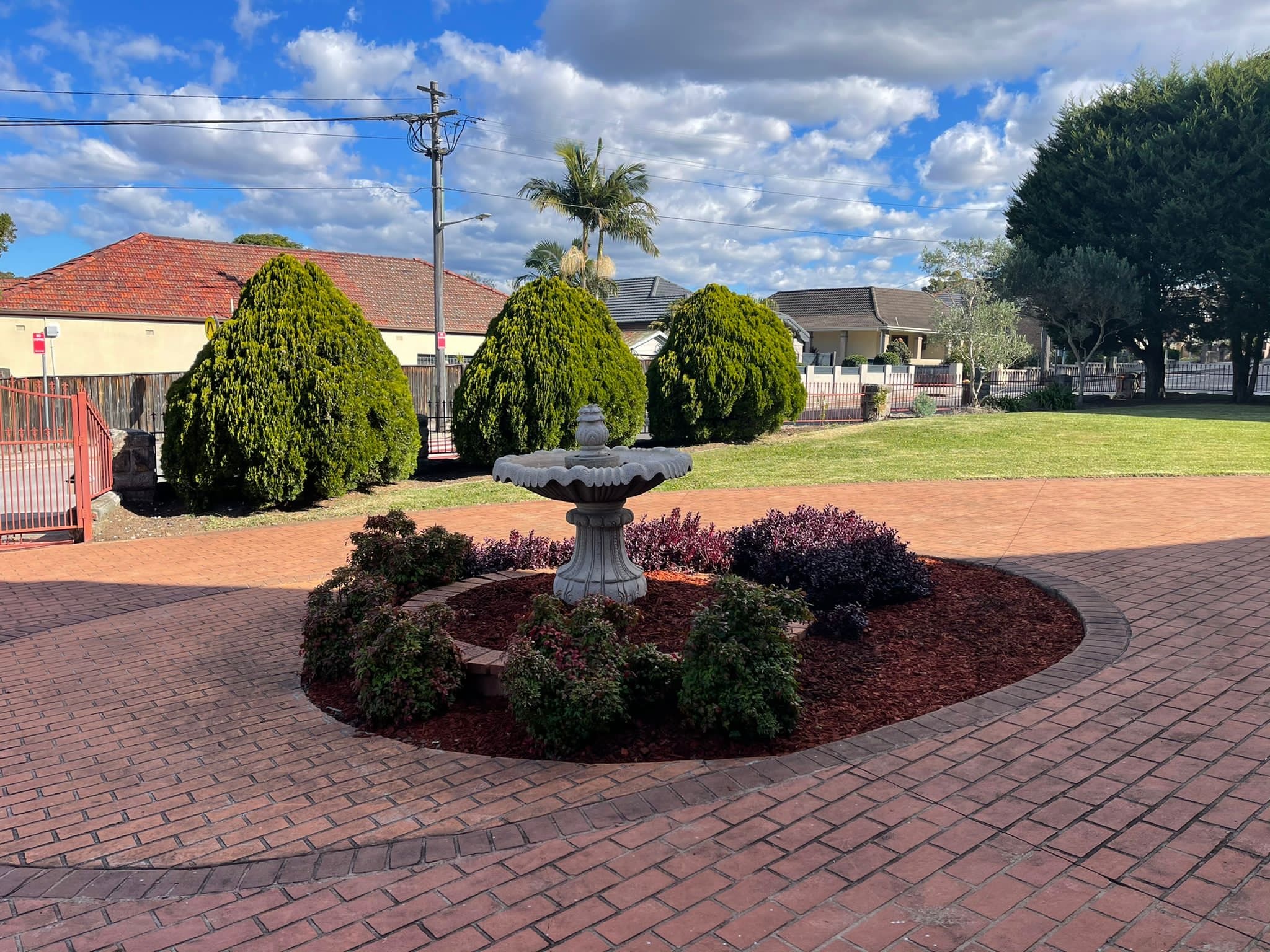 Maintained lawn, trimmed hedges and a landscaped garden bed around a fountain